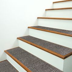 a set of stairs with black and white patterned carpet on the bottom, and wooden handrails