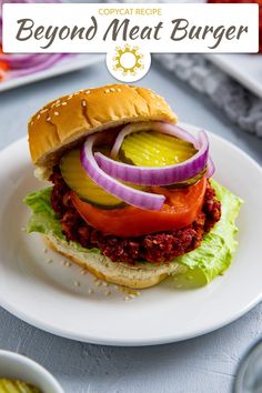 a plate with a sandwich on it that has onions, tomato and cucumber