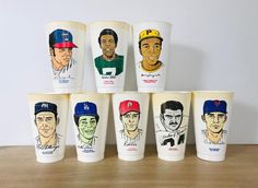 a group of cups with different baseball players painted on the lids and sides, all lined up in a row