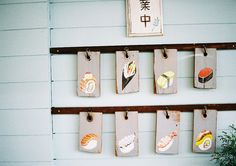 several pieces of wood hanging on a wall with sushi images attached to them and a potted plant in the foreground