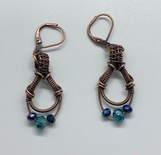 Elegant Wire wrapped Copper Earrings with Blue Crystals and Copper leverback ear wires.An original Monkeylion Design.Approximately 1 7/8" long from the top of the ear wire and 5/8" wide.These earrings have been antiqued, polished and sealed.Sealed with ProtectaclearProtectaClear is a clear, protective coating that is tough enough to protect jewelry and is safe for wear against skin. ProtectaClear is practically invisible once applied and will seal and protect jewelry from tarnish, oxidation, and Copper And Blue, Blue Crystal Earrings, Silver Earrings Handmade, Copper Earrings, Blue Crystals, Ear Wire, Ear Wires, Crystal Earrings, Earrings Handmade