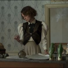 a woman standing in front of a table with an open book on top of it