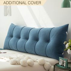 a blue pillow sitting on top of a bed next to a table with flowers and pictures