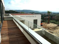 a balcony with wooden flooring and glass railings on the side of a building