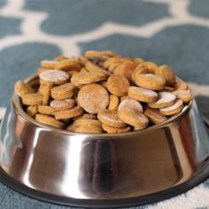 a metal bowl filled with cat food on top of a blue and white carpeted floor