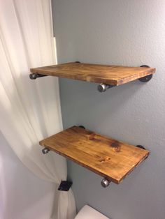 two wooden shelves on the wall above a toilet