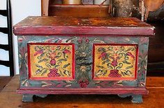 an old wooden chest with painted designs on the front and side panels, sitting on a table