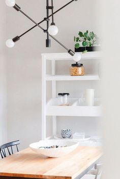 a dining room with a wooden table and white shelves