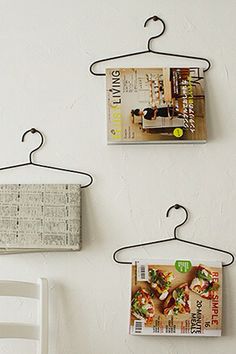 there are two pictures hanging on the wall with clothes pins attached to them and one has a magazine in it