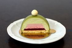 a piece of cake sitting on top of a white plate covered in green and pink icing