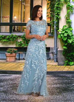 a woman standing in front of a building wearing a blue dress