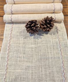 three pine cones sitting on top of a table next to some burlocked fabric