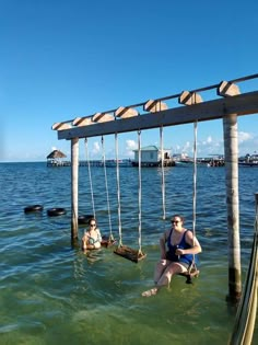 two people sitting on swings in the water