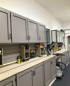 a room filled with lots of gray cabinets and workbench tools on top of it