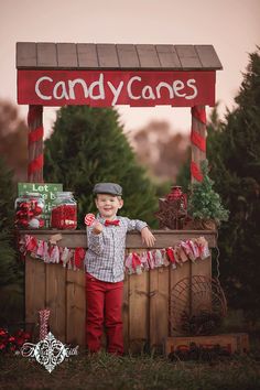 a little boy standing in front of a candy cane stand