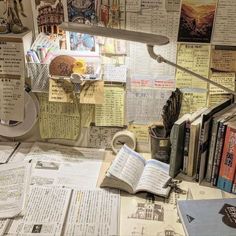 a cluttered desk with many books and papers on the top, including an open book