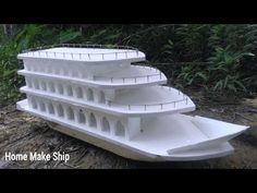 a large white boat sitting on top of a dirt ground next to trees and bushes