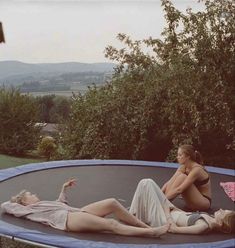 two women laying on top of a trampoline