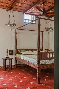 a bed sitting inside of a bedroom on top of a red tiled floor next to a table