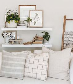 a living room filled with lots of white furniture and plants on top of the shelves