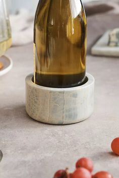 a bottle of wine sitting on top of a table next to some grapes and tomatoes