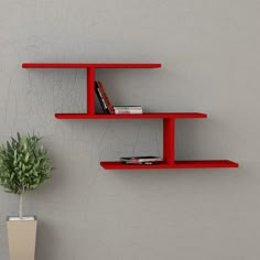 two red shelves on the wall next to a potted plant and bookshelf