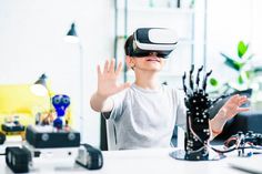 a young boy wearing a virtual reality headset sitting at a desk in an office