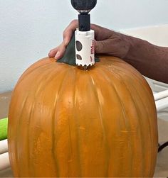 a person is painting a pumpkin with an electric paintbrush on it's head