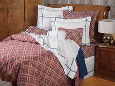 a bed with red and white comforter in a bedroom next to a night stand