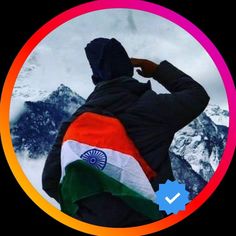 a man standing on top of a snow covered mountain next to a rainbow colored circle