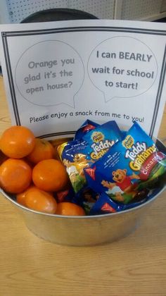 a metal bowl filled with candy and oranges on top of a wooden table next to a sign that says i can bearly go it's the wait for school to start