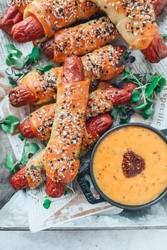 hotdogs wrapped in pretzels and dipping sauce on a tray with breadsticks