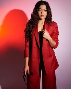 a woman in a red suit posing for the camera with her hand on her hip