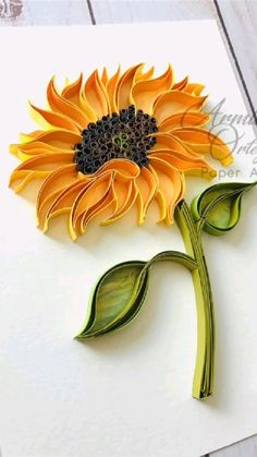 a sunflower made out of paper sitting on top of a piece of white paper