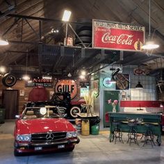 an old car is parked in a garage with other antique cars and signs on the walls