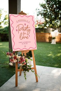 a sign that says party for love on it in front of some grass and flowers