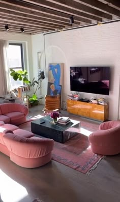 a living room filled with pink furniture and a flat screen tv mounted on the wall