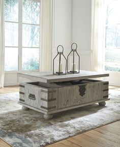 an old trunk coffee table with two candles on it in front of a large window