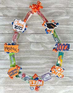 a wreath made out of candy on top of a wooden table with the words class of 202 spelled in different languages