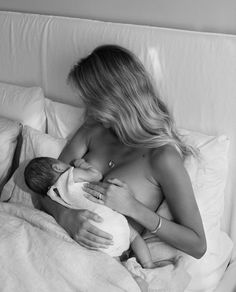 a woman is breastfeeding her baby on the bed in black and white photo