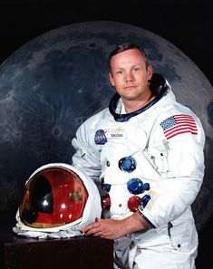 a man in an astronaut's suit standing next to a large object with the moon behind him