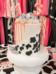 a white and black cake sitting on top of a table covered in pink and black decorations