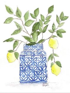 a blue vase filled with lemons and green leaves on top of a white surface