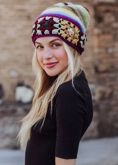 a woman with blonde hair wearing a multicolored crocheted beanie hat