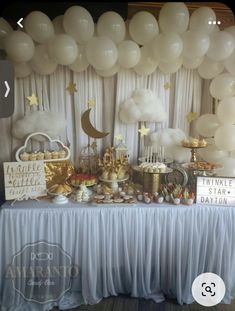 a table topped with lots of white balloons and desserts next to a curtained wall