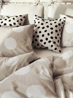 a bed topped with lots of pillows covered in polka dot sheets and pillow shampoos