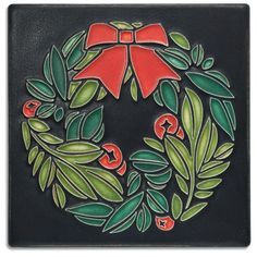 a decorative tile with a red bow and holly wreath on the front, surrounded by green leaves