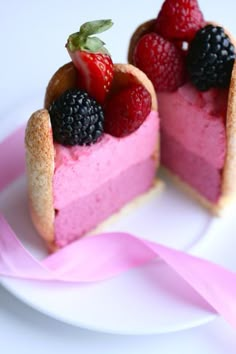 two small desserts on a plate with pink ribbons and strawberries in the shape of hearts