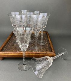 an assortment of crystal wine glasses on a wooden tray