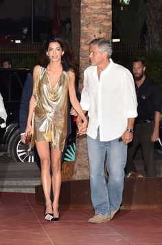 the man and woman are walking down the street holding hands, both dressed in gold